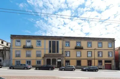 a large yellow building with cars parked in front of it at Douro Central in Porto