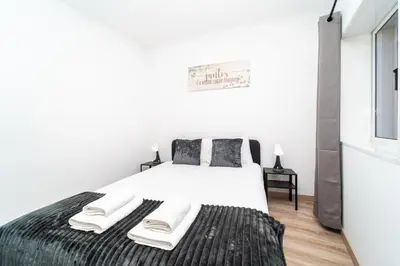 a bedroom with a large bed with white sheets and a window at Gaia Family Nest in Vila Nova de Gaia
