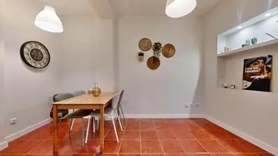 a dining room with a table and chairs and a clock at Porto Sweet Home in Porto