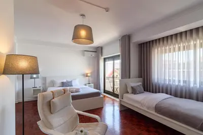 a hotel room with two beds and a chair at Lindo Vale Guest House in Porto