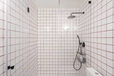 a white tiled bathroom with a shower with a basket at GuestReady - Joy Apartments in Porto