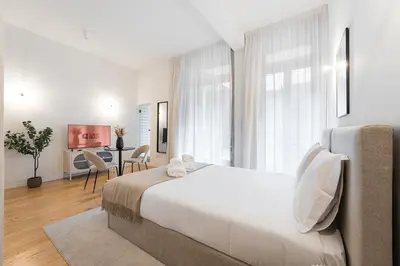 a white bedroom with a large bed and a desk at GuestReady - Joy Apartments in Porto