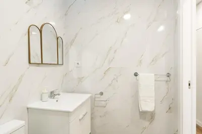 a white bathroom with marble walls and a sink at VIVA Spacious Apartment Campanhã in Porto