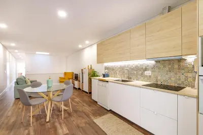 a kitchen with white cabinets and a table and chairs at VIVA Spacious Apartment Campanhã in Porto