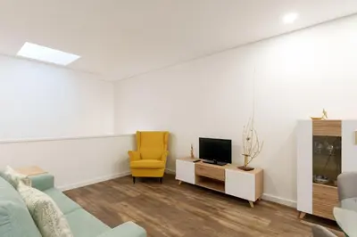 a living room with a yellow chair and a tv at VIVA Spacious Apartment Campanhã in Porto
