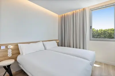a white bedroom with a large bed and a window at B&B HOTEL Porto Centro Massarelos in Porto