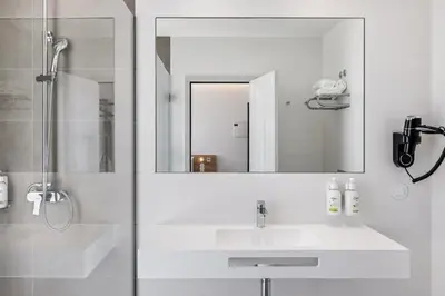 a white bathroom with a sink and a mirror at B&B HOTEL Porto Centro Massarelos in Porto