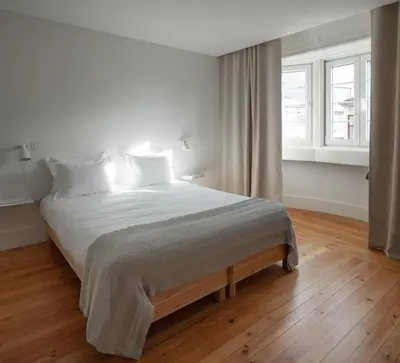 a white bedroom with a large bed with white sheets at Santa Catarina 555 T4 in Porto