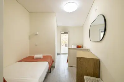 a small bedroom with a bed and a mirror at D&S - Torne 187 in Vila Nova de Gaia