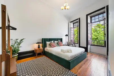 a bedroom with a bed and two windows at Terraced Apartment in the Heart of Porto - Free Parking in Porto