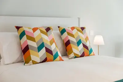 a white bed with two colorful pillows on it at Douro Tower Loft - Shared Pool in Vila Nova de Gaia