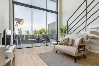 a living room with a chair and large windows at Douro Tower Loft - Shared Pool in Vila Nova de Gaia