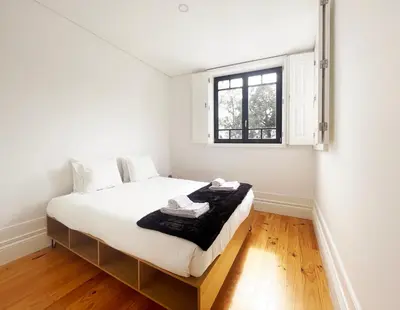 a white bedroom with a bed with a window at MariPinto Downtown Apartment in Porto