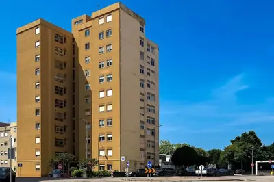 a tall yellow building in a parking lot at Vintage Copio Apartment in Vila Nova de Gaia