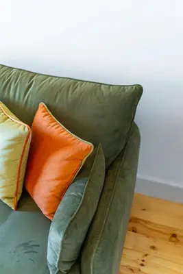 a green couch with two orange pillows on it at Lifestyle at Porto by Upperground in Porto