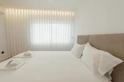 a bedroom with a white bed with white sheets and pillows at Downtown Premium With Balcony by Vacationy in Porto