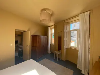 a room with a bed and a window and a table at Sunny Apartment in Porto