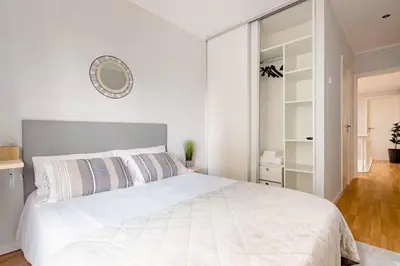 a white bedroom with a large white bed and a mirror at Typical Oporto House in Porto
