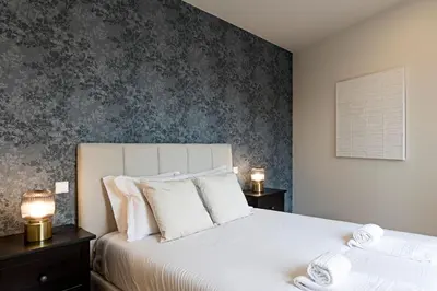 a bedroom with a white bed with a gray wall at Superb Flat w Balcony and AC by LovelyStay in Porto