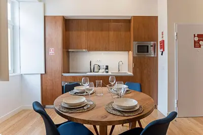 a kitchen with a wooden table and blue chairs at Superb Flat w Balcony and AC by LovelyStay in Porto