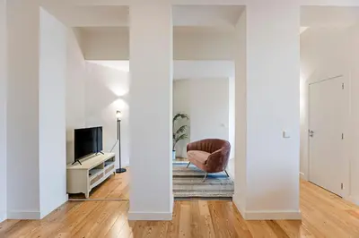 a living room with white walls and a chair and a television at Superb Flat w Balcony and AC by LovelyStay in Porto