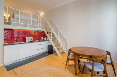 a kitchen and dining room with a table and a staircase at Almada 151 - 2F in Porto