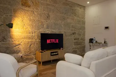 a living room with a tv in a stone wall at T2 Pedra do Bonfim, Centro do Porto com Pátio e Churrasqueira in Porto
