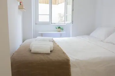 a bedroom with a white bed with towels on it at T2 Pedra do Bonfim, Centro do Porto com Pátio e Churrasqueira in Porto