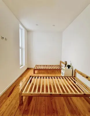 two beds in an empty room with wooden floors at Porto Boavista Patio House in Porto