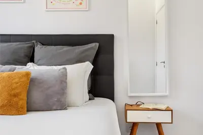 a bed with grey and white pillows and a side table at GuestReady - Fantastic Porto Flat in Porto