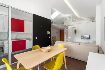 a kitchen and dining room with a wooden table and yellow chairs at Rosario Duplex in Porto