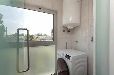 a bathroom with a washing machine and a window at Rosario Duplex in Porto