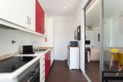 a kitchen with white counters and red cabinets at Rosario Duplex in Porto