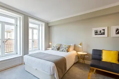 a bedroom with a bed and a chair and windows at Historical Corner by Upperground in Porto