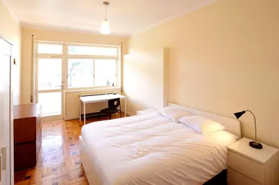 a bedroom with a large white bed and a desk at School Santos Pousada in Porto