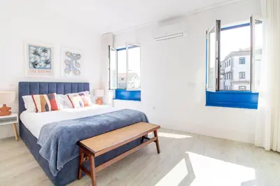 a bedroom with a bed and two windows at Bom Retiro's Delight by LovelyStay in Porto