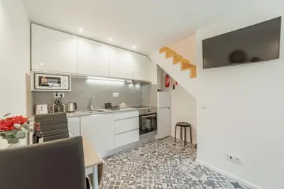 a kitchen with white cabinets and a table and chairs at Cedofeita Loft by Hosty in Bicas
