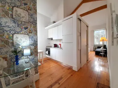 a kitchen with white cabinets and a wooden floor at Azulejos Loft, by Flat in Porto in Porto