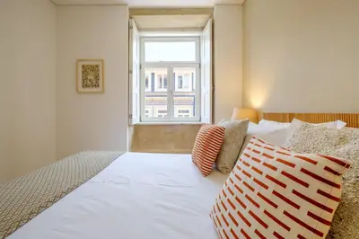 a bedroom with a large white bed with a window at Porto Cedofeita Urban Charm Residence in Porto