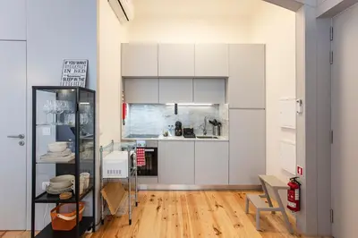 a kitchen with white cabinets and a hardwood floor at Modern Retro Downtown by LovelyStay in Porto