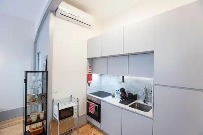 a kitchen with white cabinets and a sink at Modern Retro Downtown by LovelyStay in Porto