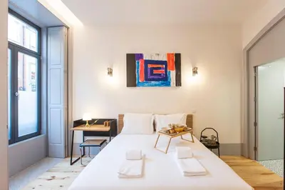 a bedroom with a large white bed and a table at Modern Retro Downtown by LovelyStay in Porto