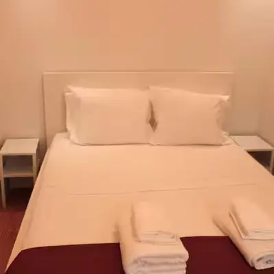 a bed with two pillows and two towels on it at Alegria Street Flat in Porto