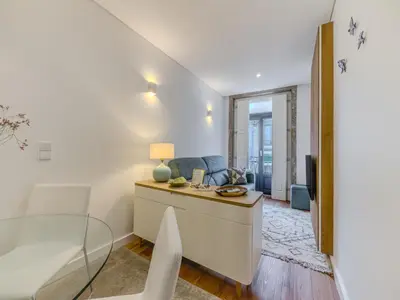 a living room with a bed and a table with a lamp at Almada Comfy in Porto
