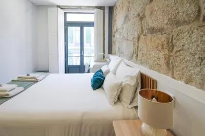a bedroom with a white bed with a stone wall at Almada Comfy in Porto