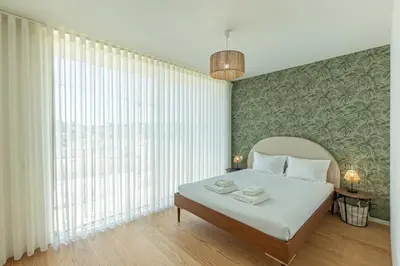 a bedroom with a bed and a large window at GuestReady - Urban luxury with Douro view in Vila Nova de Gaia