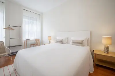 a white bedroom with a large white bed and a table at Casa Verde by Olala Homes in Porto