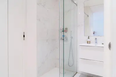 a white bathroom with a shower and a sink at Studio w/ Balcony, Pool & Gym | Antas by Host Wise in Porto
