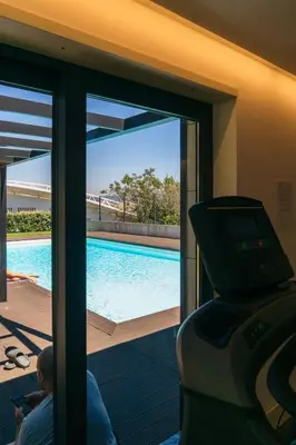 a man sitting in front of a sliding glass door with a swimming pool at Studio w/ Balcony, Pool & Gym | Antas by Host Wise in Porto