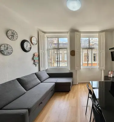 a living room with a couch and clocks on the wall at Oporto Good Vibrations -Downtown in Porto